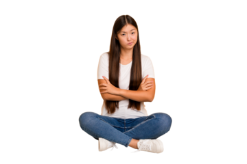 Young asian woman sitting on the floor cutout isolated suspicious, uncertain, examining you.