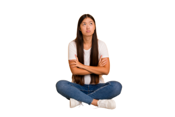 Young asian woman sitting on the floor cutout isolated tired of a repetitive task.