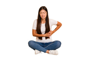 Young asian woman sitting on the floor cutout isolated having a liver pain, stomach ache.