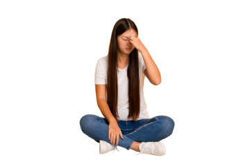 Young asian woman sitting on the floor cutout isolated having a head ache, touching front of the face.