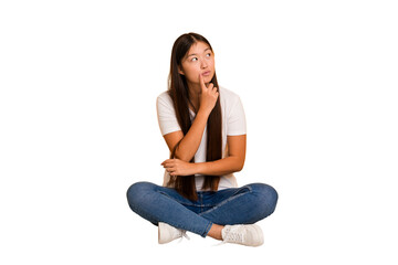 Young asian woman sitting on the floor cutout isolated contemplating, planning a strategy, thinking...