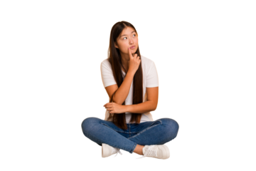 Young asian woman sitting on the floor cutout isolated contemplating, planning a strategy, thinking about the way of a business.
