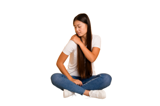Young asian woman sitting on the floor cutout isolated having a shoulder pain.