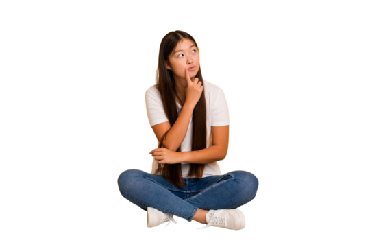 Young asian woman sitting on the floor cutout isolated contemplating, planning a strategy, thinking about the way of a business.
