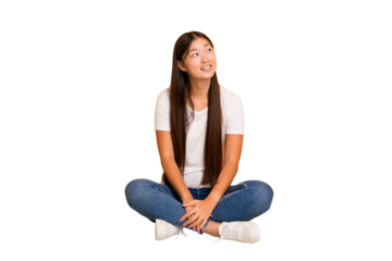 Young asian woman sitting on the floor cutout isolated relaxed and happy laughing, neck stretched showing teeth.