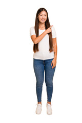Fototapeta premium Young asian woman standing, full body cutout isolated smiling and pointing aside, showing something at blank space.