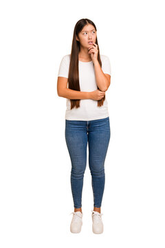 Young asian woman standing, full body cutout isolated looking sideways with doubtful and skeptical expression.