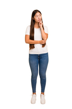 Young asian woman standing, full body cutout isolated looking sideways with doubtful and skeptical expression.