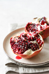 Nahaufnahme von einem rohen Granatapfel mit Kernen auf einem beigen Tisch. 