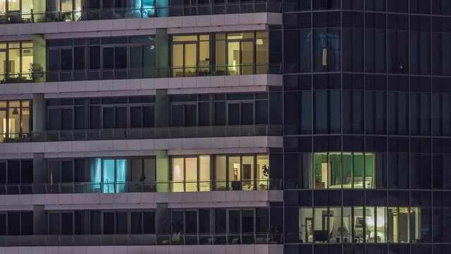 Windows lights in modern office and residential buildings timelapse at night. Multi-level skyscrapers with illuminated apartments inside