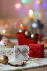 Various colorful Christmas decorations, soft blanket, cup of tea, sweet snacks and lit candles on the table. Cozy Christmas atmosphere at home. Selective focus.