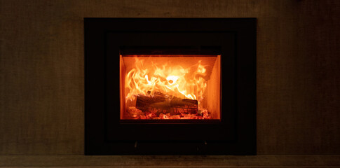 Fire flames and burning wood logs, fireplace on a wall, warm home in winter
