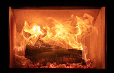 Fototapeta premium Fire flames and burning wood logs, energy stove fireplace close up,