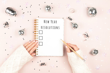 2023 year goals. Woman writing in notepad with New Year resolutions and holiday decor. Plan,...