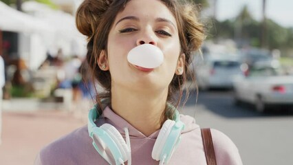 Fashion, summer and face of girl with bubble gum stand in city street on holiday, vacation and weekend in Miami. Beauty, travel and happy girl blowing bubbles with headphones, trendy and cool clothes