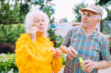 Old modern couple dressing fashionable colored clothes. Youthful grandmother and grandfather having...