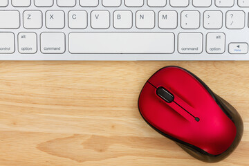 Red mouse with a keyboard on a wood desk