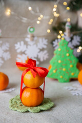 Fototapeta na wymiar tangerines with a red bow and Christmas tree cookies on the table