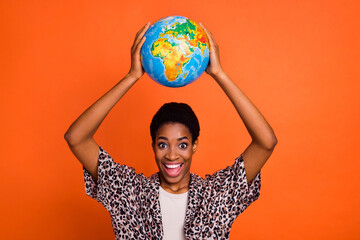 Portrait of attractive cheerful trendy girl holding globe over head eco system isolated over bright...