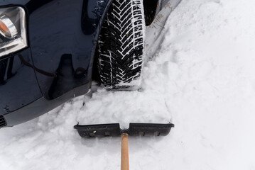 Transportation,winter,people and vehicle concept. Man digging snow with shovel near car in cold...