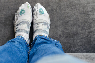 A man is in blue pants jeans lying in bed with an image of an American dollar on his sock.Indoors shot,selective focus.Closeup.Copy space.