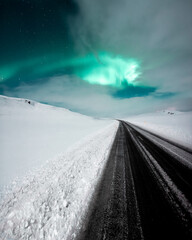 Aurora borealis, northern lights over the road, dancing queen on the clear sky during winter,...