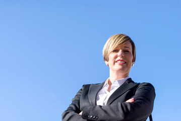 Low angle portrait of a young businesswoman standing outdoors and crossing her arms. Low-angle shot