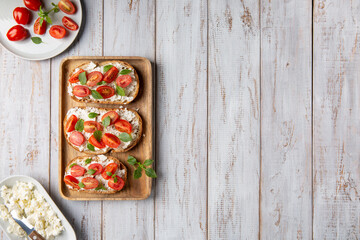 Sandwich with cottage cheese, tomatoes and basil on white wooden background. Traditional Italian...