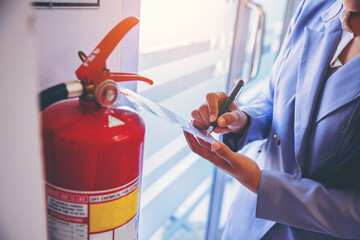 woman worker inspection chemical Fire extinguisher and fire hose. writing on monthly check...