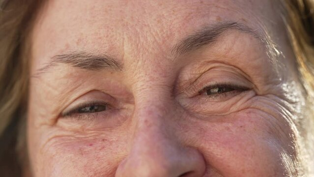 One happy Senior woman macro closeup of Eyes smiling. Aged female person in 70s with wrinkles looking at camera