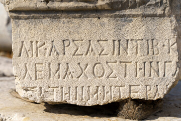 Antique greek inscriptions carved on the stone of the old ruins of an antique greek city