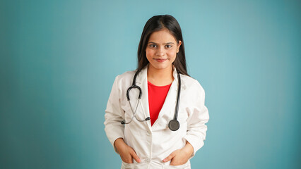 Portrait of a young female doctor wearing apron and stethoscope, Cheerful Asian Indian woman doctor isolated over blue studio background