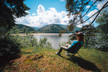 Girl enjoy the view on the mountain overlooking the lake. They sit on folding portable camping chairs. Concept of equipment for tourism and vacation. Active lifestyle. Tereblya, Ukraine