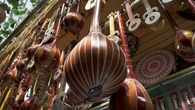 Traditional Handcrafted Uygur String Instrument Dutars Hanging In A Musical Instrument Store In Urumqi, Xinjiang, China. low angle, panning