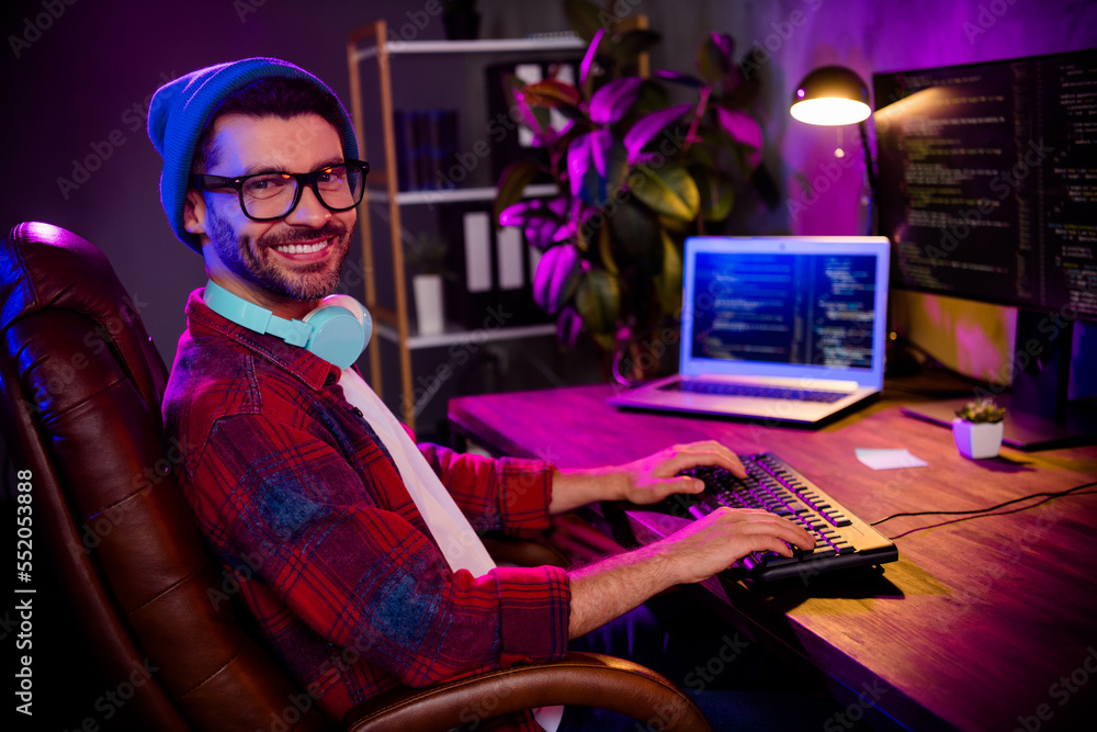 Poster photo of happy smiling programmer wear spectacles hat creating software modern device indoors workpl