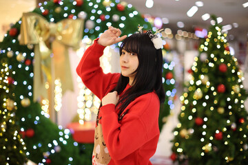 Beautiful Asian young woman with a red sweater with Christmas tree light