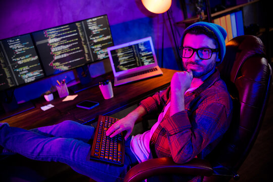 Photo of smiling cool guy dressed glasses hat thinking fulfil coding tasks indoors workstation workshop home