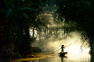 Photo of a local asian old man male boatman wearing conical hat rowing a small wooden boat across a...