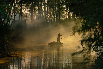 Photo of a local asian old man male boatman wearing conical hat rowing a small wooden boat across a...