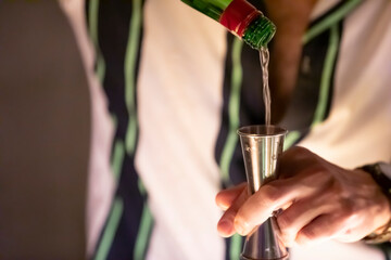 Pouring alcohol into cocktail jigger.