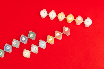 Multicolored cans with pens for drawing on a red background