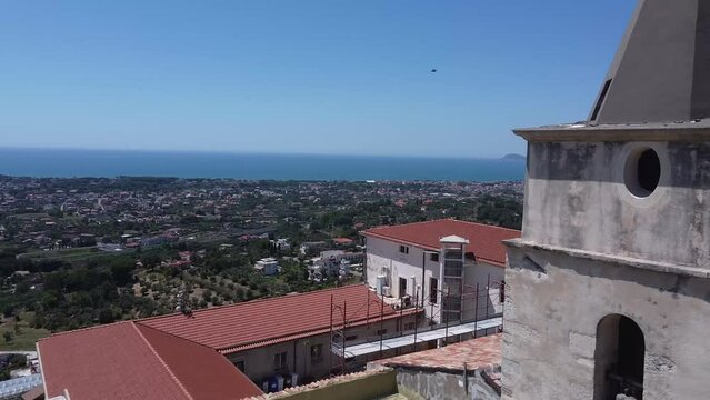 Ancient stone bell tower and cityscape of Formia, aerial fly forward view