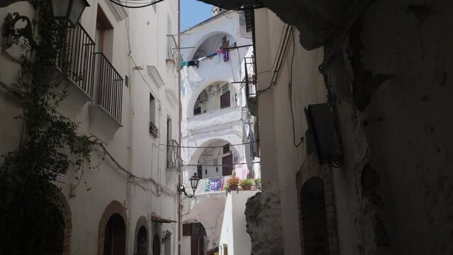 Narrow passageway through white building into small yard, Formia city