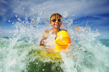 Portrait of boy in orange sunglasses with yellow inflatable duck