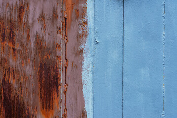 Metal surface with traces of rust and faded paint. A half painted and half rusty metal wall.