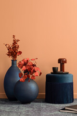 Aesthetic composition of living room interior with navy pouf, vase with red dried flowers, carpet,...