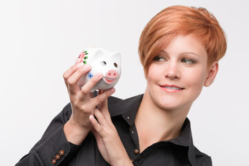 Fototapeta na wymiar young red haired woman with a piggy bank