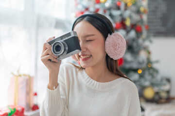 Cute beautiful young asian lady woman wearing earmuffs holding an vintage film camera and posing...