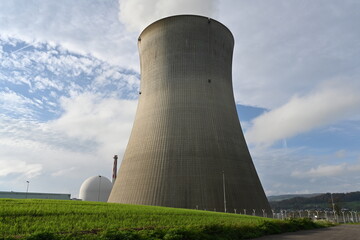 Huge cooling tower of a nuclear power plant observed from vicinity. Behind is white structure...