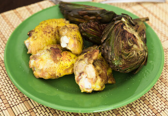 cooked fried chicken wings and halves artichokes on green plate